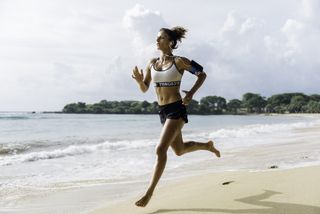 woman running barefoot on beach