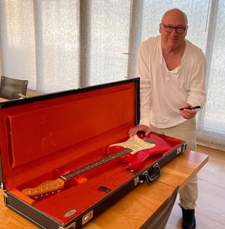 Mark Knopfler signing a red Fender Stratocaster