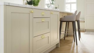 cream shaker kitchen island with beige bar stools and herringbone wooden flooring