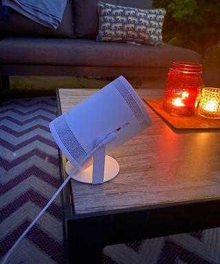 white portable projector on a garden coffee table at night