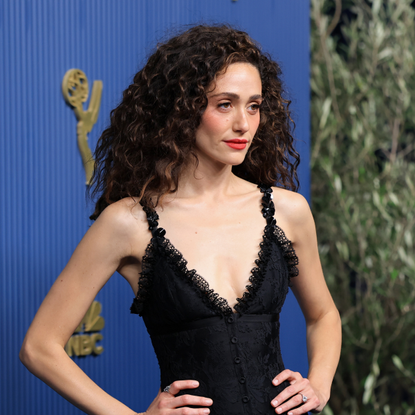Emmy Rossum wearing a black dress posing with her hands on her hips at the 2026 Emmys