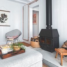 Coastal style sitting room with wood panelled walls and large wood burning stove with metal flue