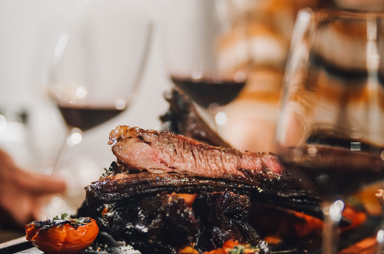 Flame-grilled meat with glasses of red wine