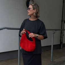 @alexisforeman wears a relaxed t-shirt, black maxi skirt and red bag