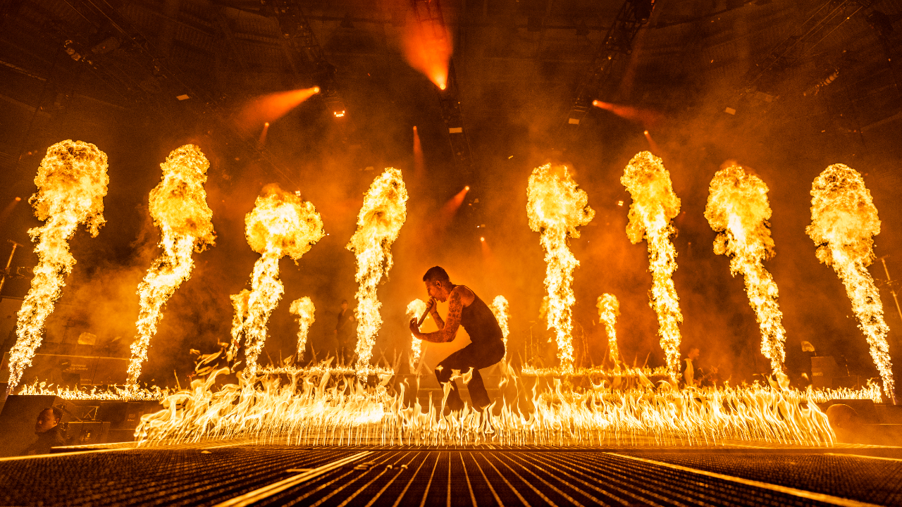 Winston McCall crouching onstage surrounded by fire