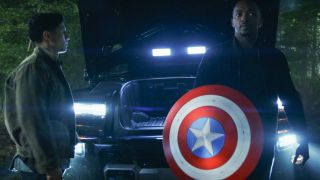 Anthony Mackie stands holding his Captain America shield while Danny Ramirez watches in Captain America: Brave New World.