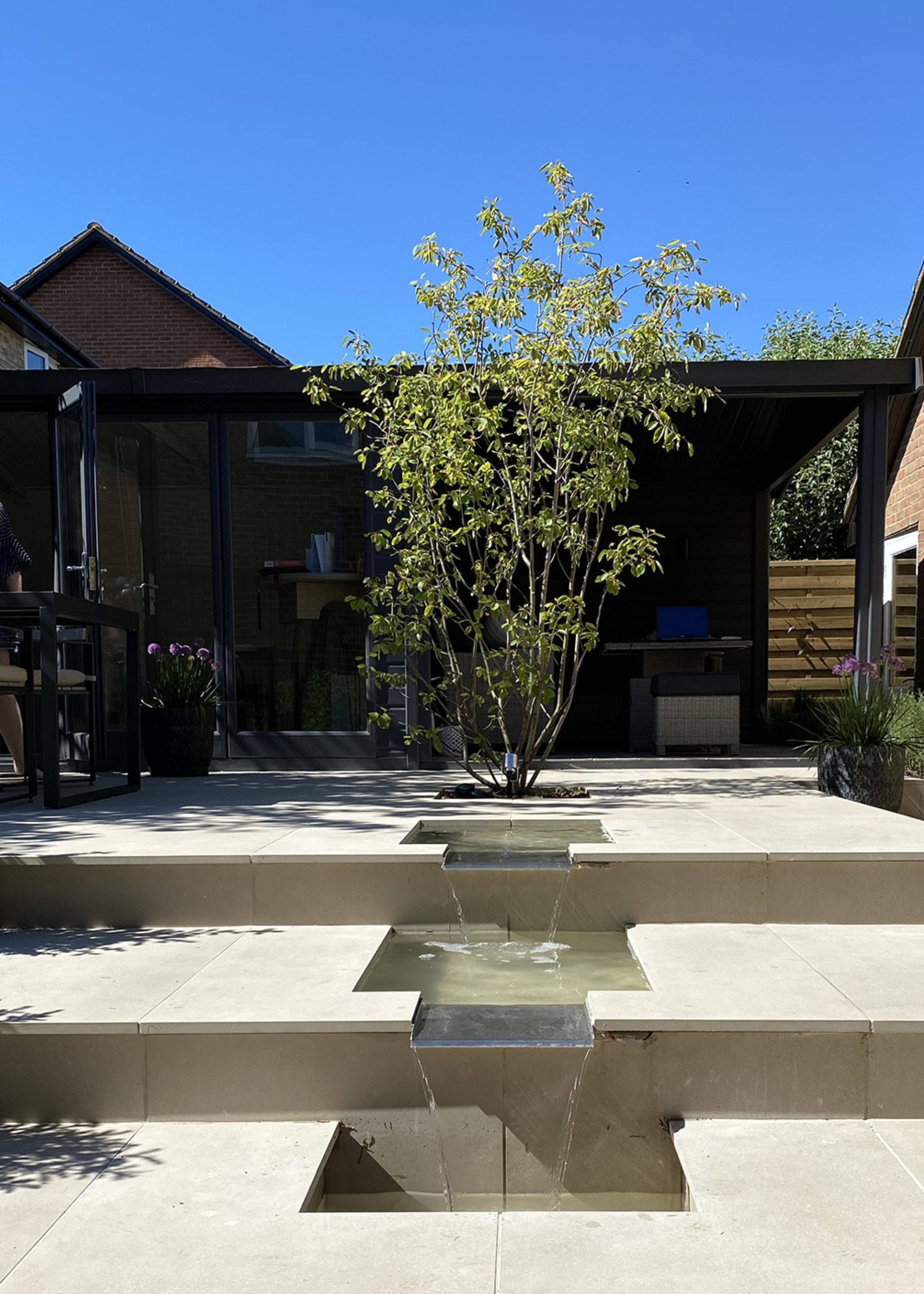 a rill in a garden with a large tree perched at the top in a backyard of a home