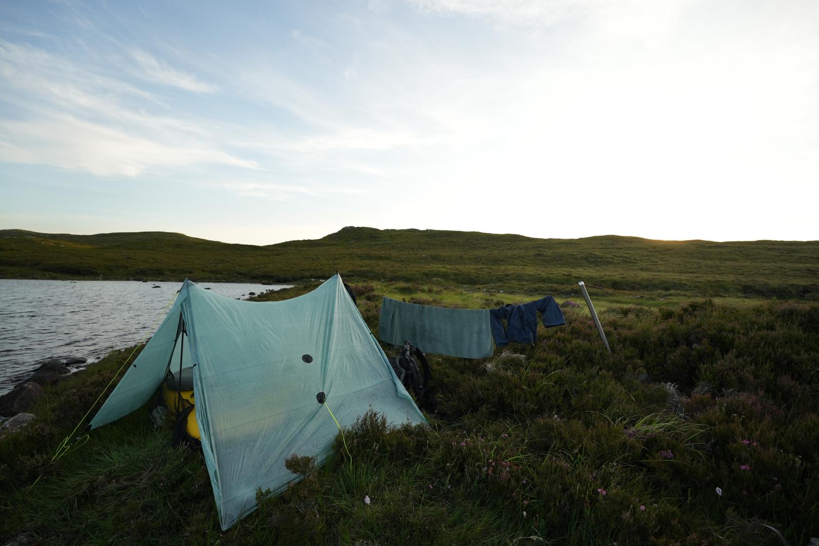 A tent near a loch, washing is hung outside