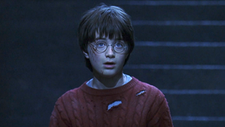 Daniel Radcliffe as Harry Potter in shock toward the end of Sorcerer's Stone with tattered red sweater and blood on his face