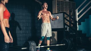 Person standing next to a barbell, shouting