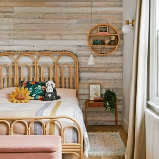 kids bedroom covered in horizontal wood panelling with a cane framed bed covered in cuddly toys