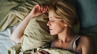 Woman sleeping peacefully on back holding pillow to neck