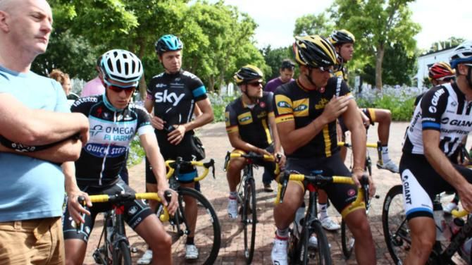 The riders listen to some pre-training information from the directeurs