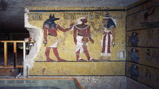 In this wall painting, Tutankhamun is flanked by the ancient Egyptian deities Anubis and Hathor. Anubis is a jackal-headed god associated with mummification, while Hathor is associated with fertility and love, among other things.