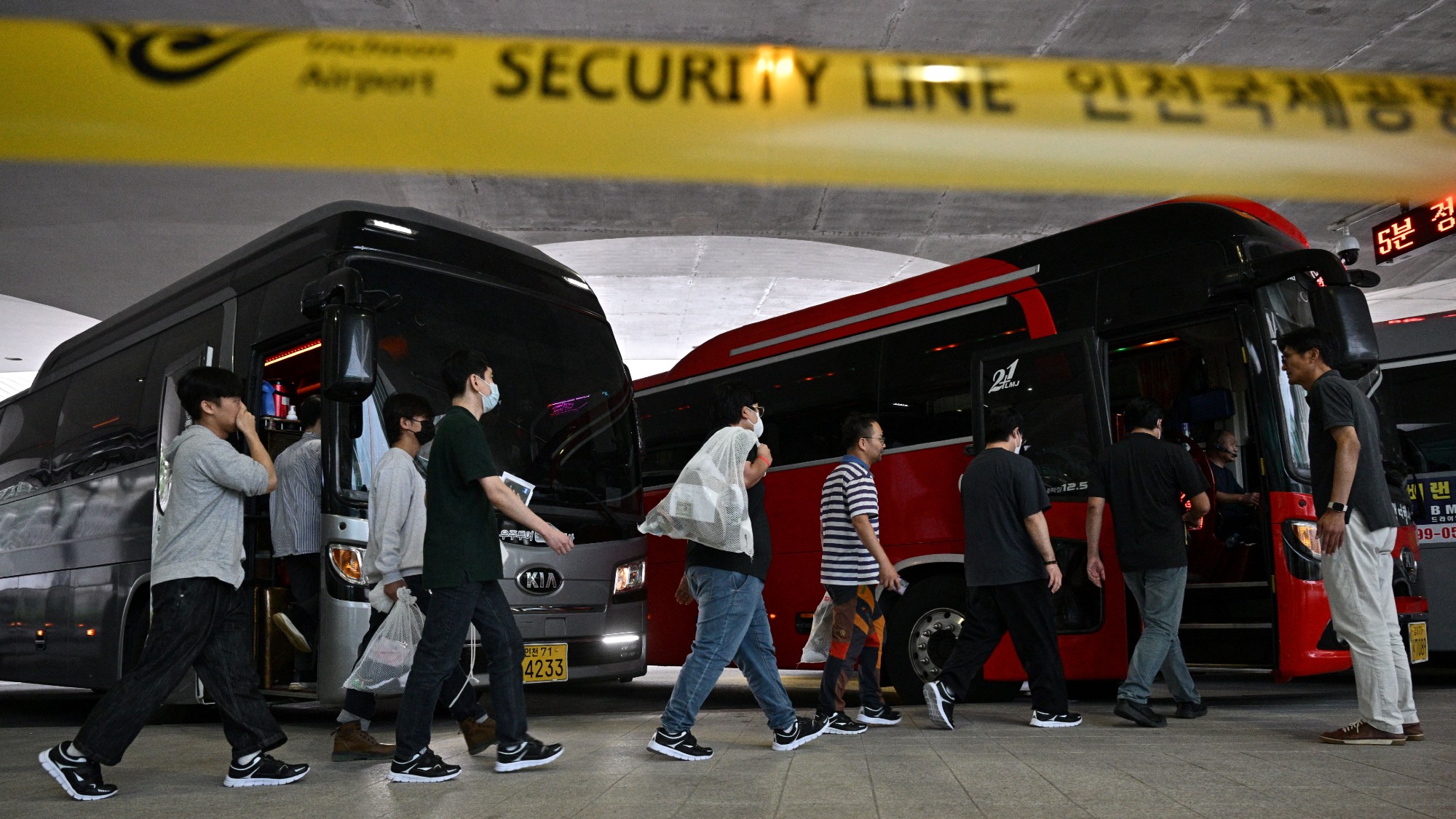 former US-based Hyundai workers in a line as they board a bus after being deported back to South Korean