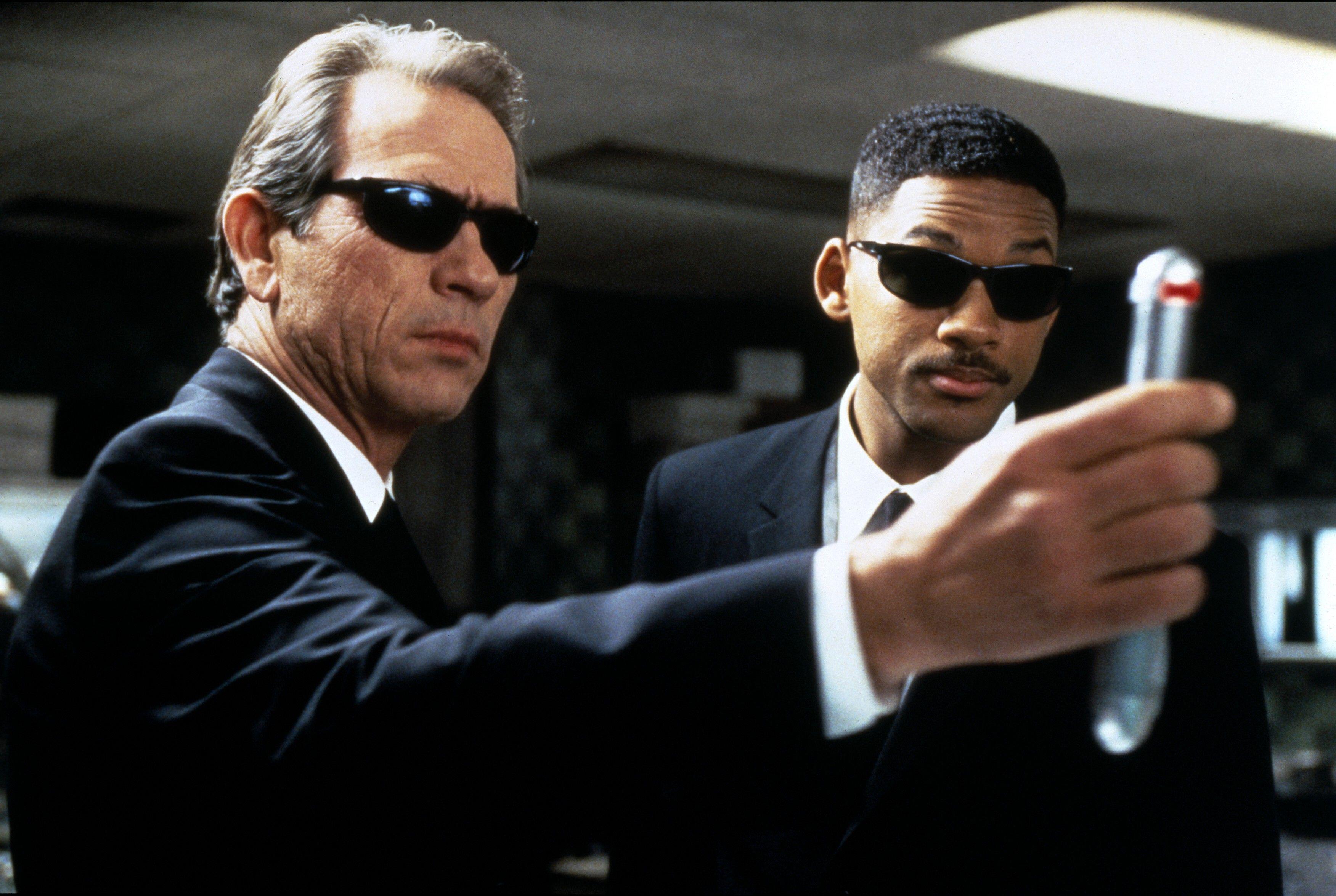 (De gauche à droite) Tommy Lee Jones en tant que K, tenant un neuralyzer, tandis que Will Smith en tant que J regarde Men In Black