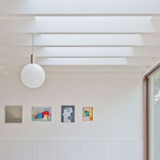 slatted roof with skylights, patio doors, pendant light and artwork on the wall