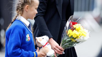 Catherine, Princess of Wales helps a schoolgirl lay her floral tribute at the entrance to Sandringham House, the Norfolk estate of Queen Elizabeth II, on September 15, 2022 in Sandringham, England. The Prince and Princess of Wales are visiting Sandringham to view tributes to Queen Elizabeth II, who died at Balmoral Castle on September 8, 2022.