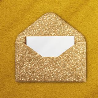 a gold sparkly envelope, open to reveal a white notecard on a gold background