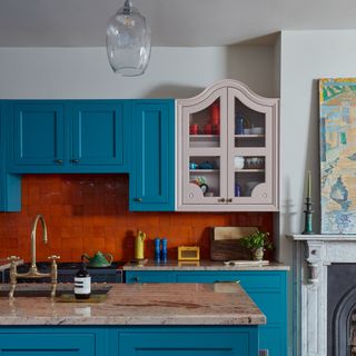 kitchen cabinets in blue and pink with a red tiled splashback