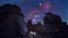 man holding a lantern on a rock formation under orion