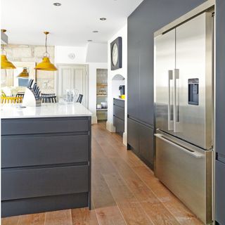 kitchen with wooden flooring, mustard pendant lights, dark grey cabinets and silver fridge freezer