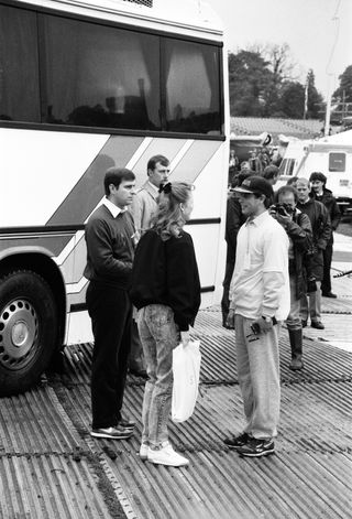 Prince Edward talking to Sarah Ferguson and Prince Andrew in front of a bus in 1987