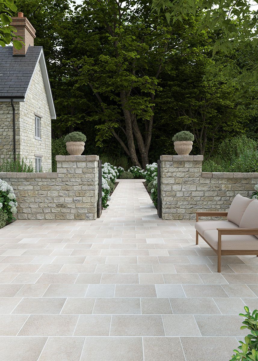 traditional paved patio with a stone wall and porcelain paving