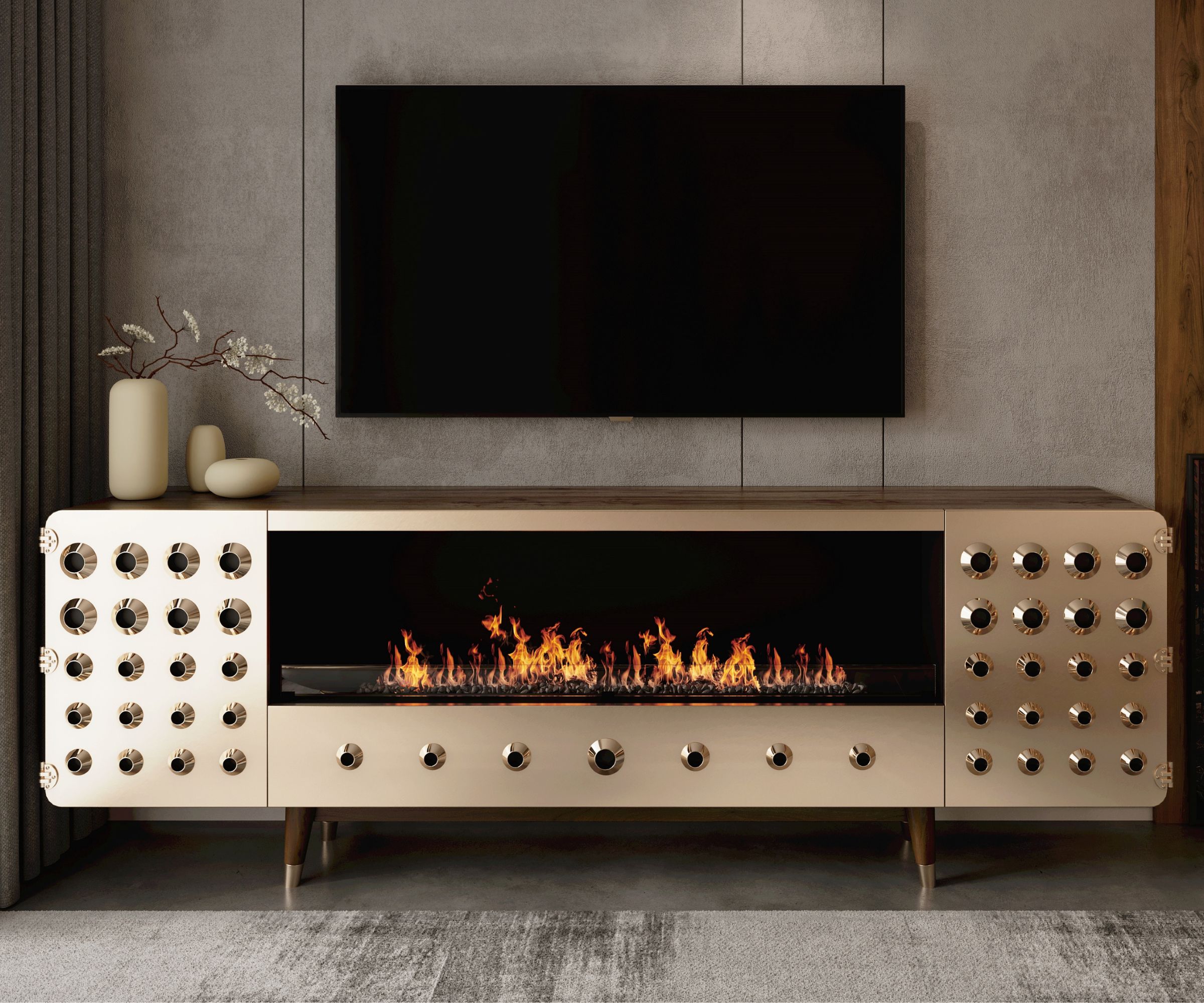 A gold-toned console with circular cut-outs holds a built-in electric fire with bright flames, set below a wall-mounted TV.