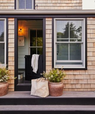 Exterior of house with wood patio stairs, large plant pots, dutch doors open