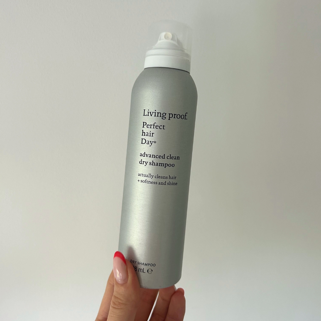 Hand holding empty silver can of Living Proof Perfect Hair Day (phd) Advanced Clean Dry Shampoo