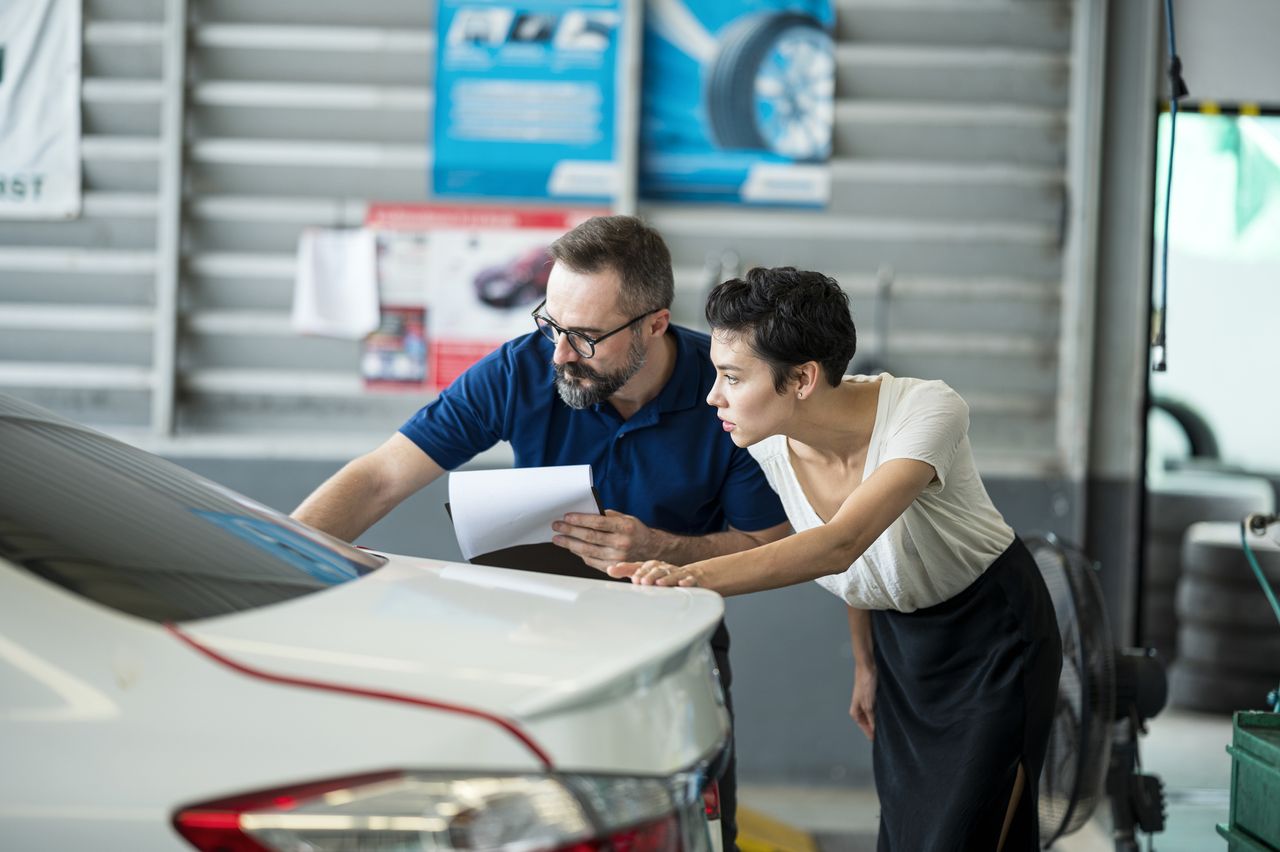 Car Insurance Claims process. Insurance agent explaining damage of car exterior to customer 