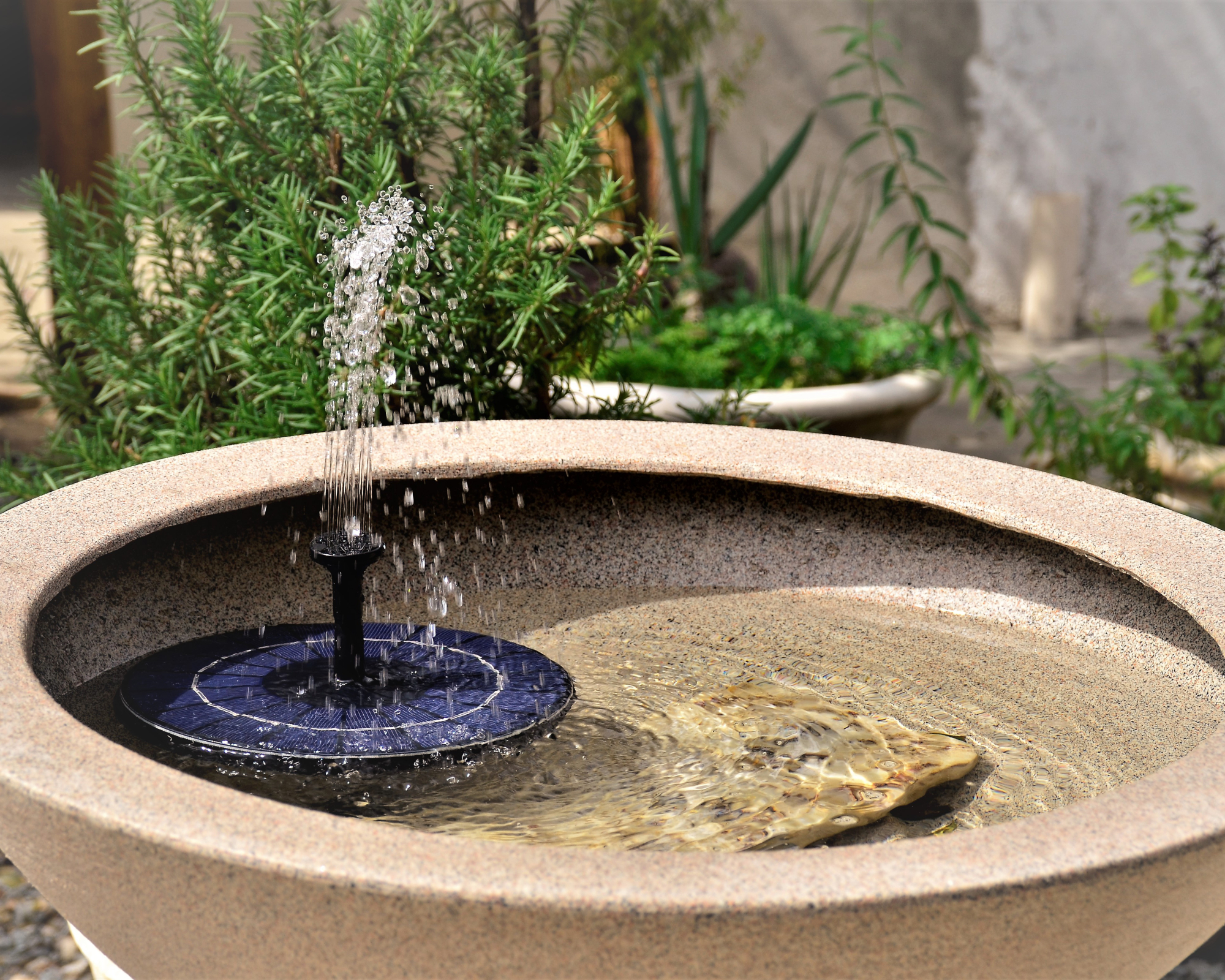 Garden water feature created from bowl planter and floating solar powered fountain