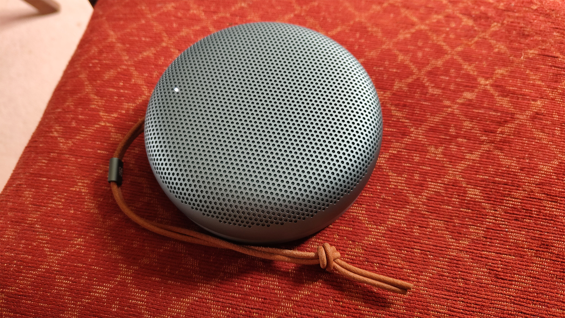 Bang & Olufsen Beosound A1 (3rd Generation) wireless speaker on red cloth surface