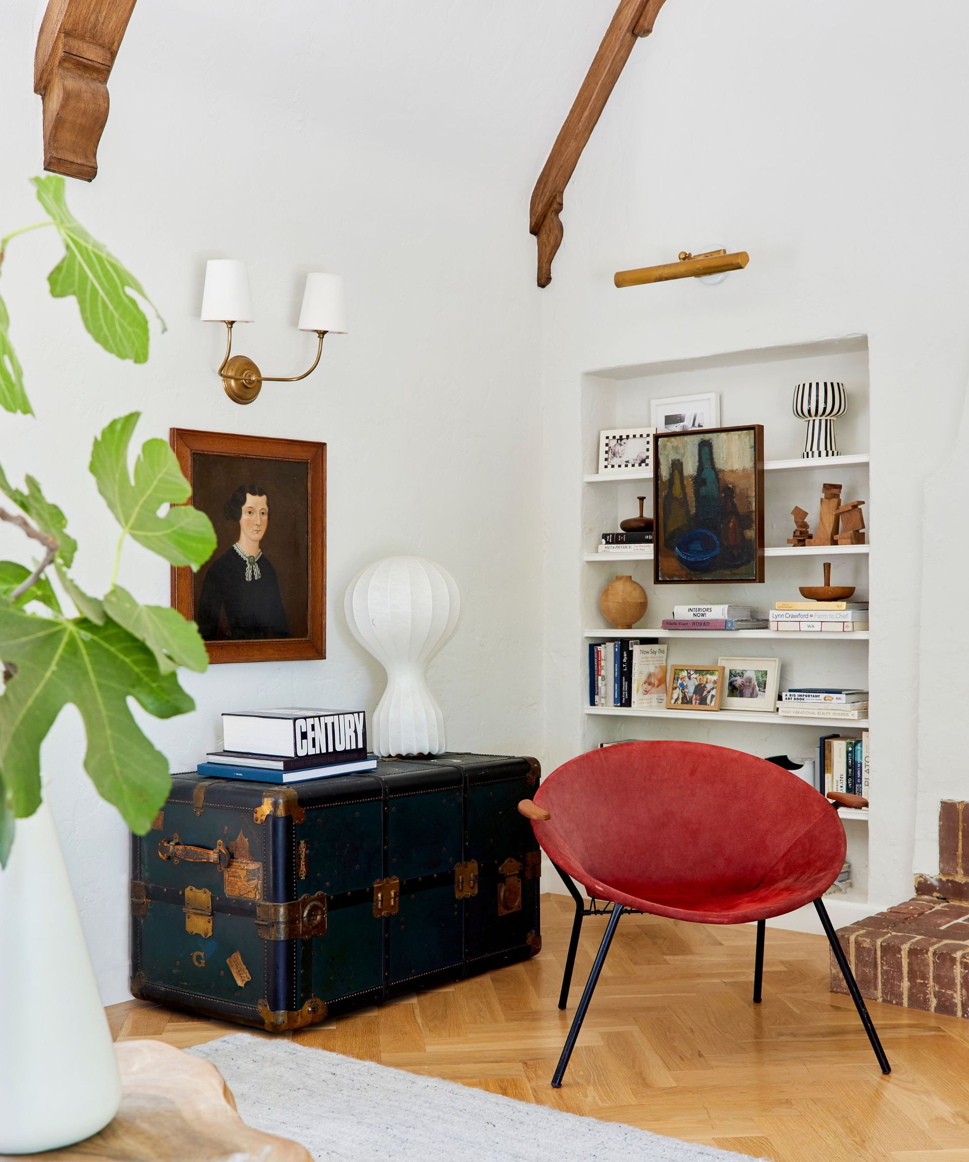 Corner of a room with antique chest of drawers and red modern chair.