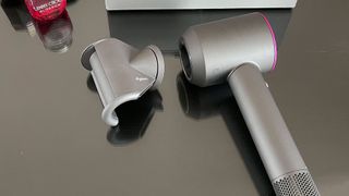 Dyson Supersonic hair dryer with fly away attachment next to it, on a dressing table