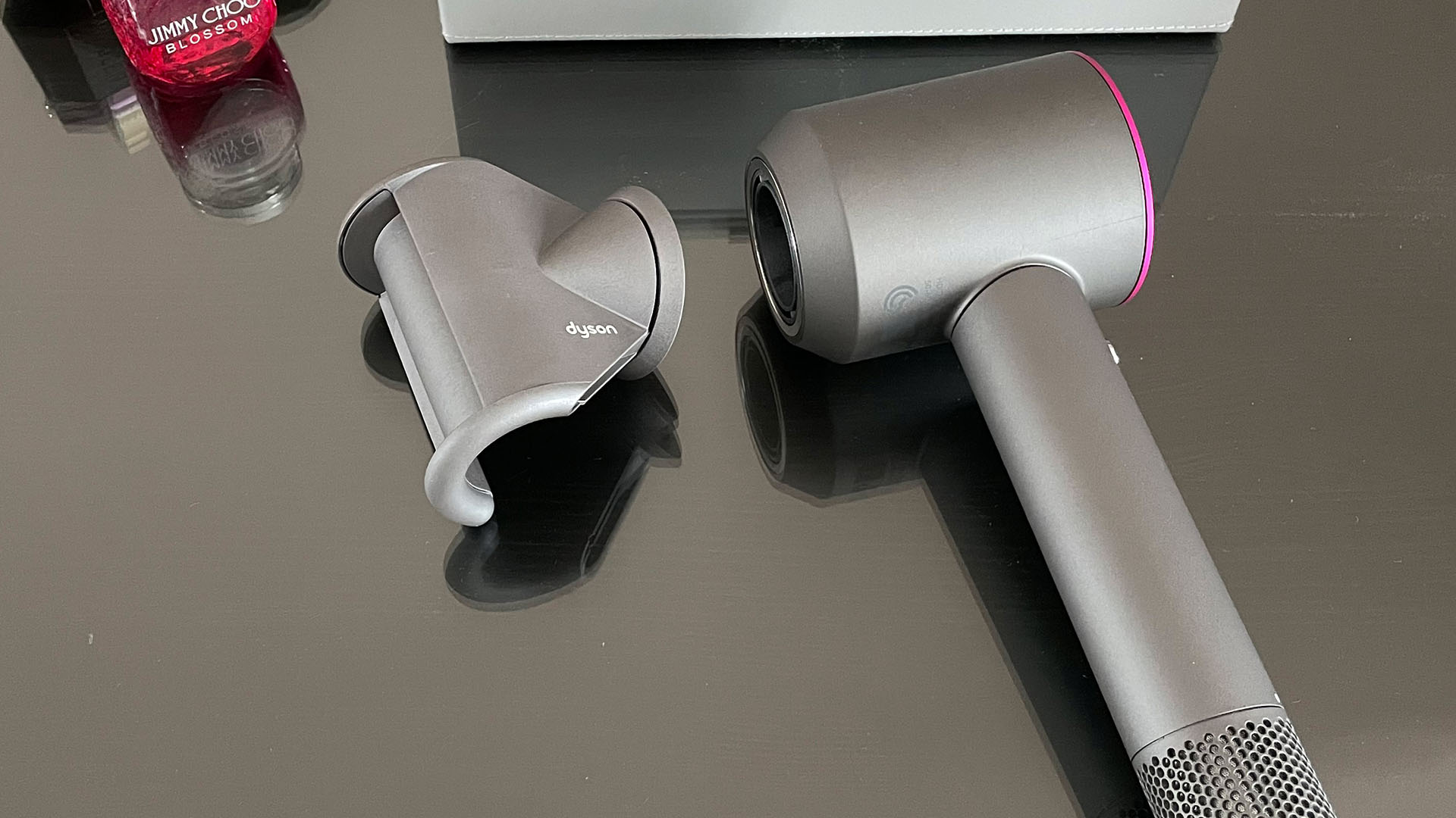 Dyson Supersonic hair dryer with fly away attachment next to it, on a dressing table