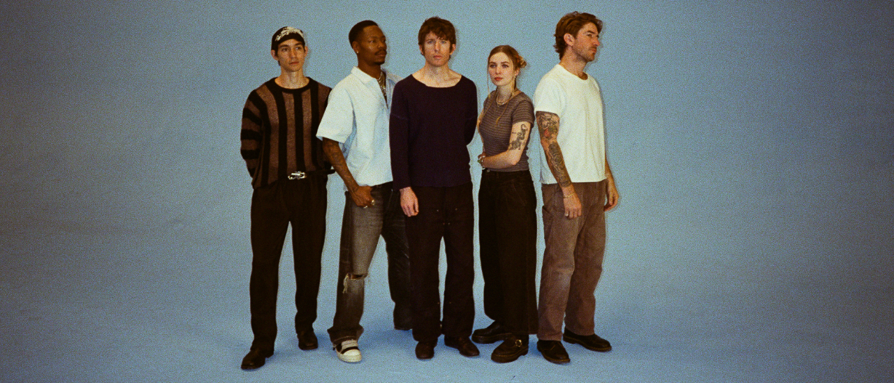 Turnstile standing serious-faced against a blue background