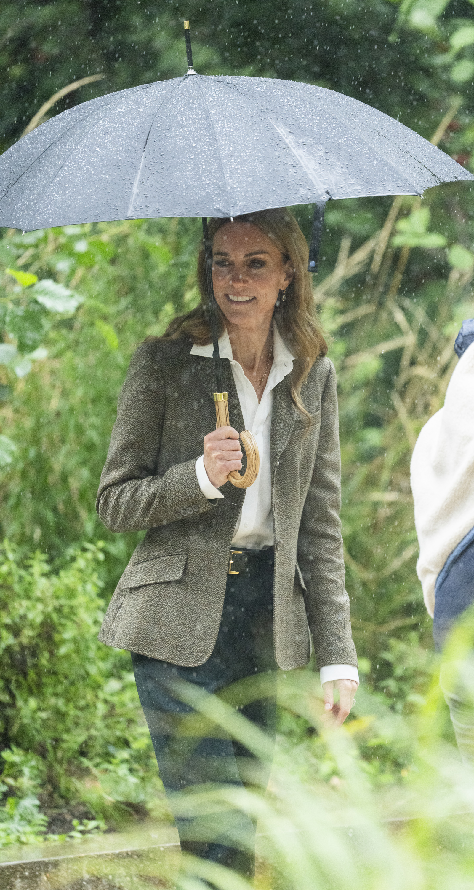 Kate Middleton holding an umbrella in a garden