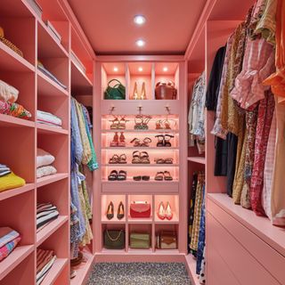 Pink painted walk in wardrobe with shoes and clothes displayed