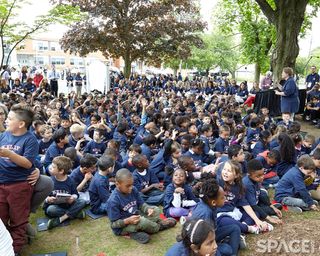 Students sitting on the grass in front of their school