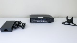 The Asus ROG NUC 970 with its included stand and AC adapter on a desk