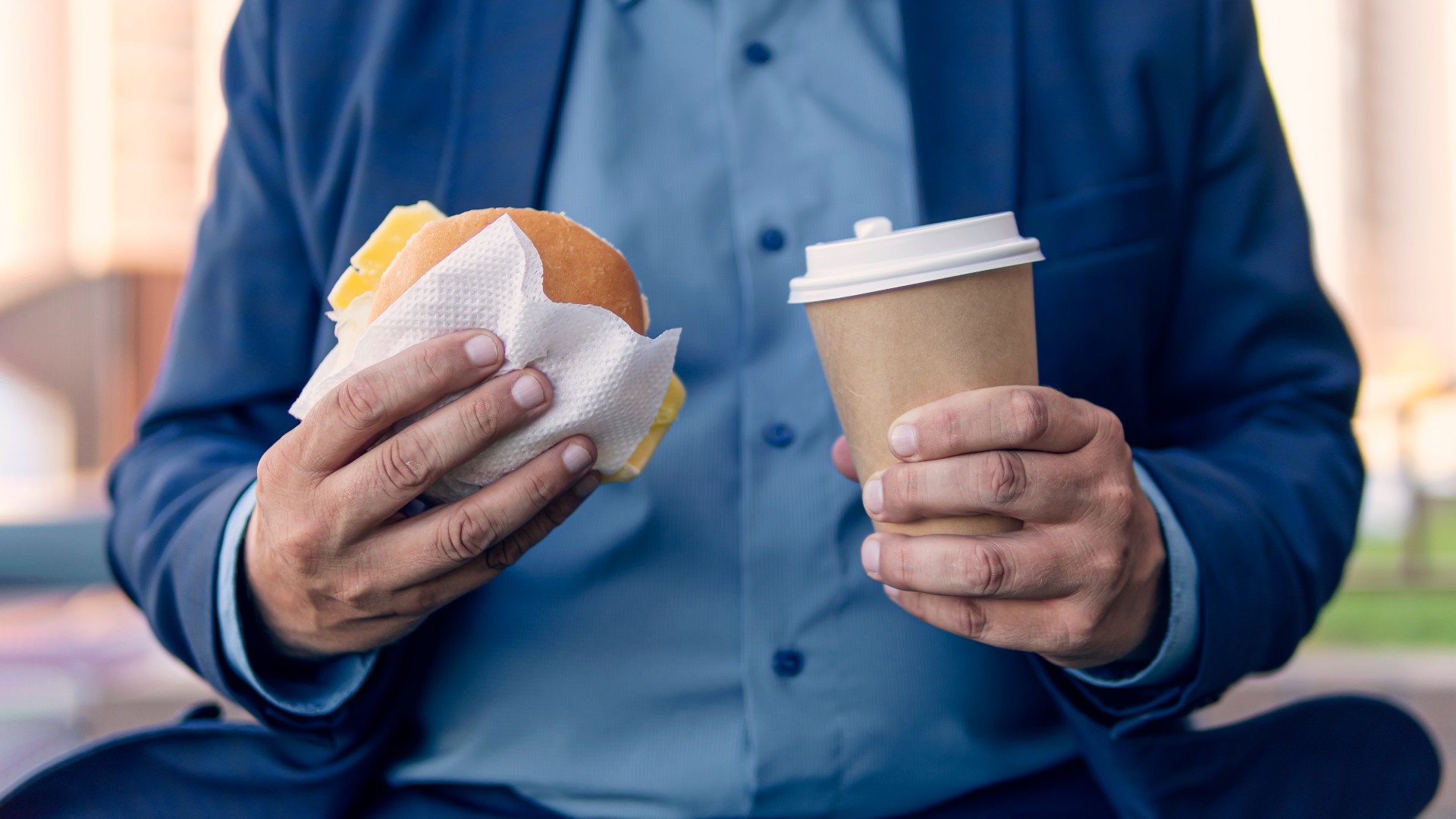 Übergewichtiger Mann mit Hamburger und Kaffee