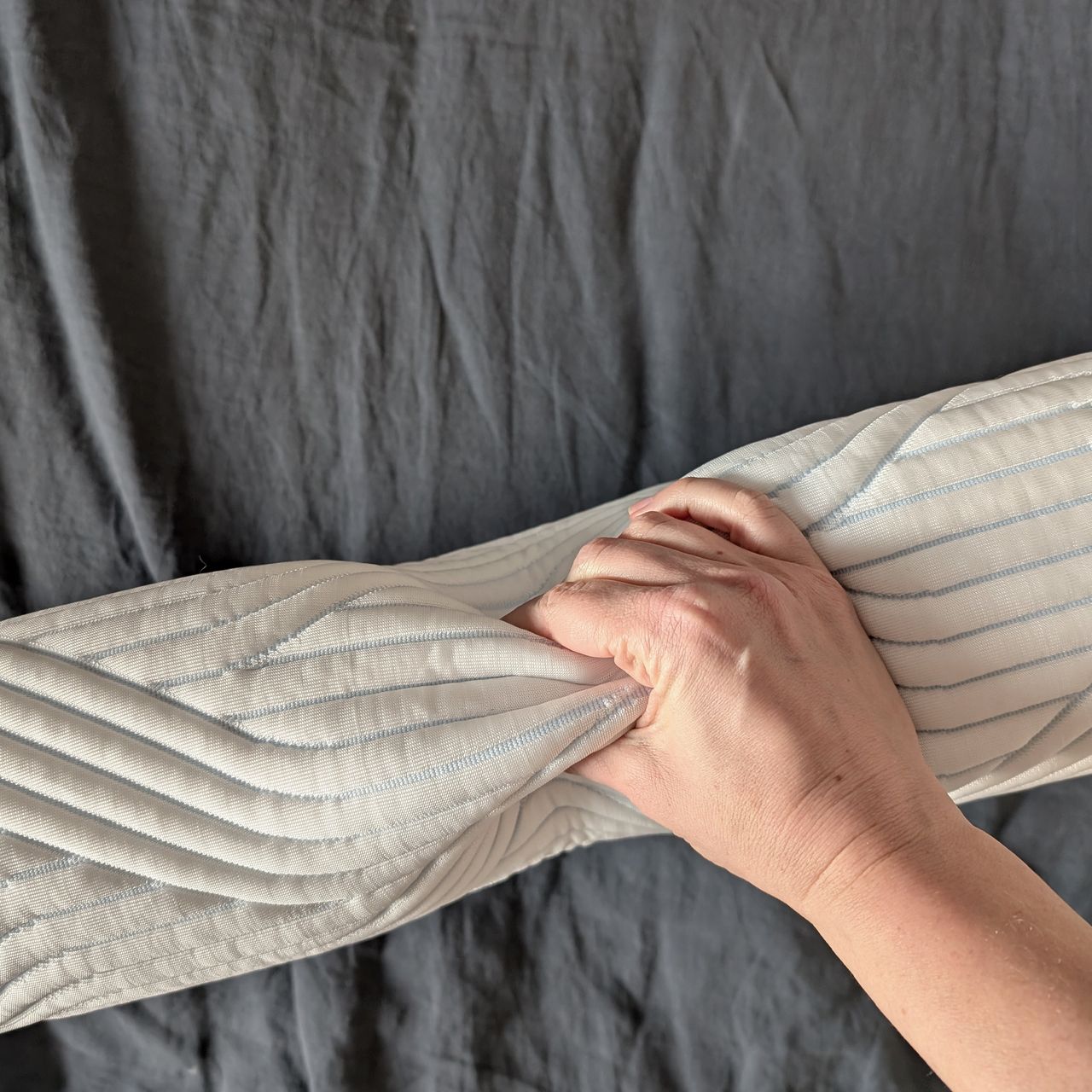 The Tempur Original SmartCool Pillow, on its side, squeezed by a hand
