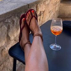 @smythsisters wears a pair of tan ankle-tie sandals whilst drinking an Aperol Spritz