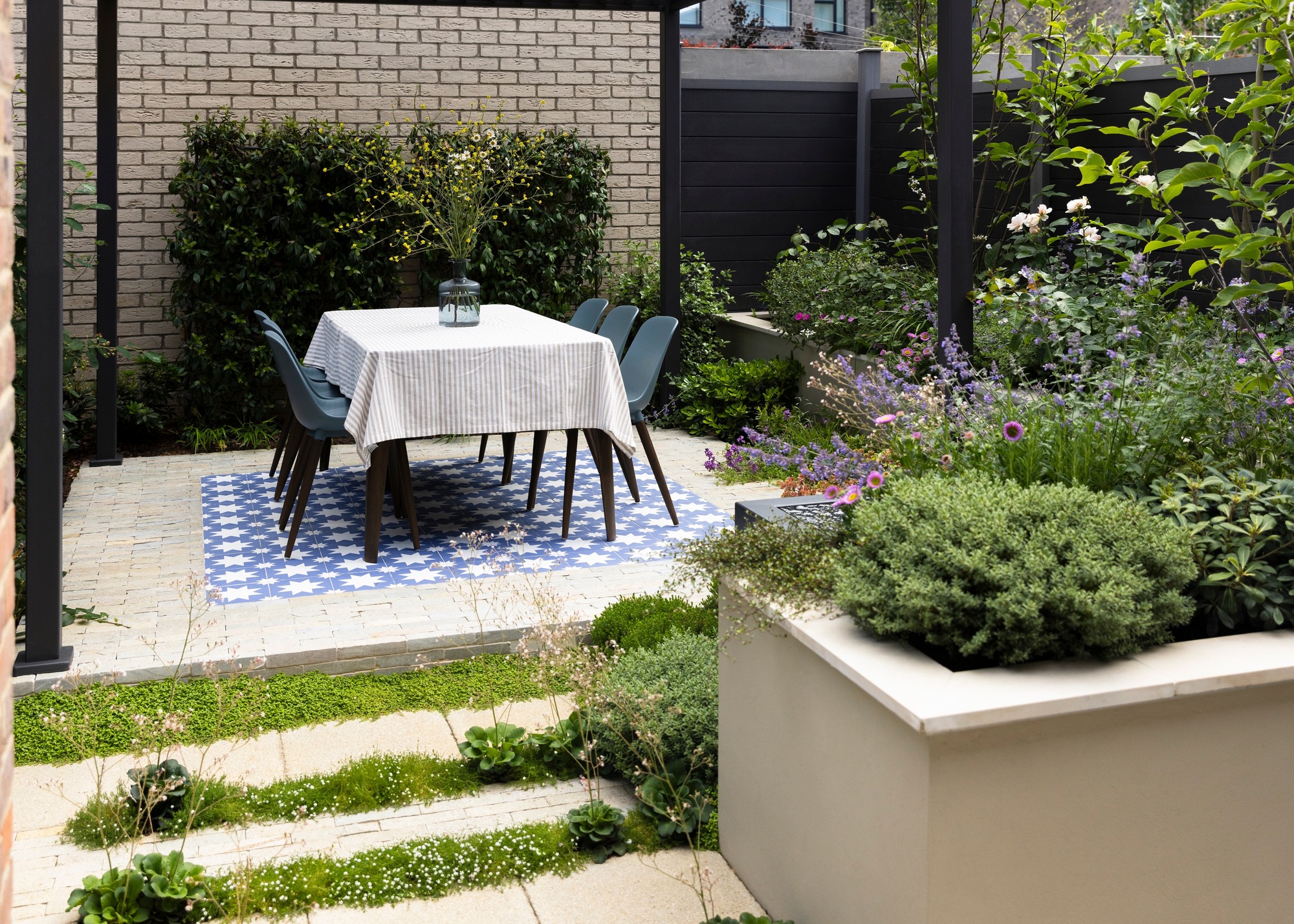 dining area under a pergola on a patio surrounded by plants