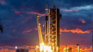 a black-and-white spacex falcon 9 rocket launches into a sunset sky.