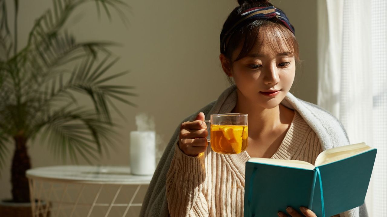 Coming off the pill: A woman drinking a cup of tea and reading a book