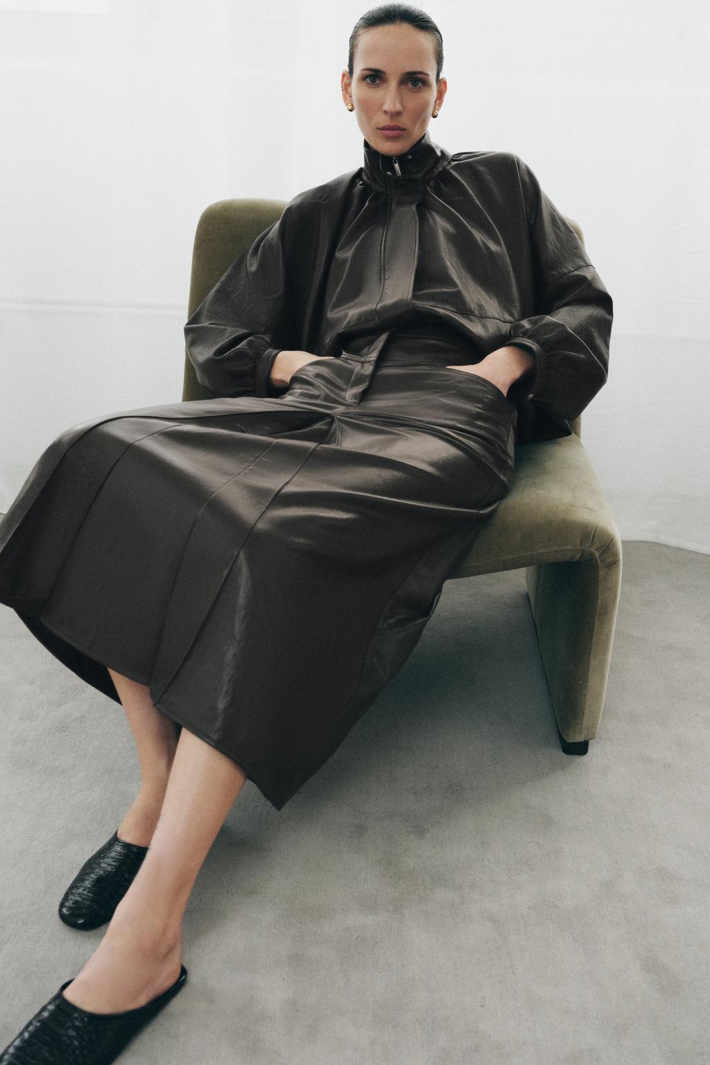 Model wears leather bomber and leather skirt with leather slides.