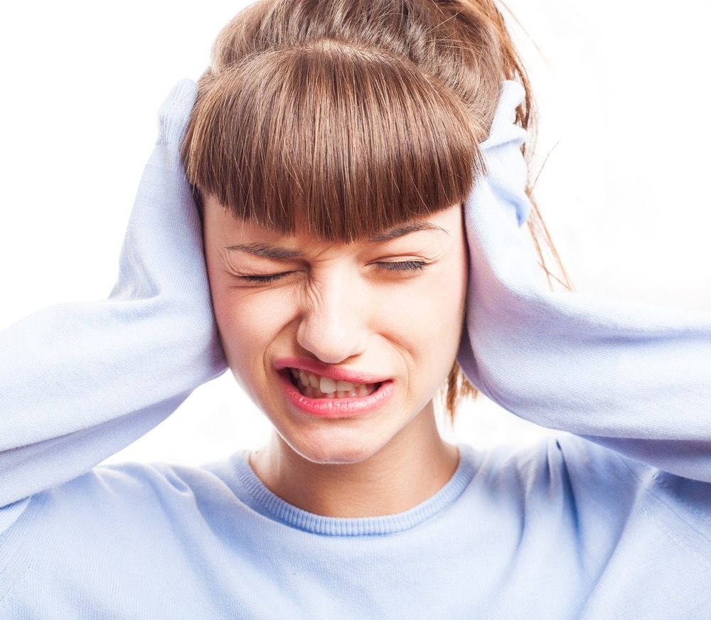 A woman holding her ears on a white background.